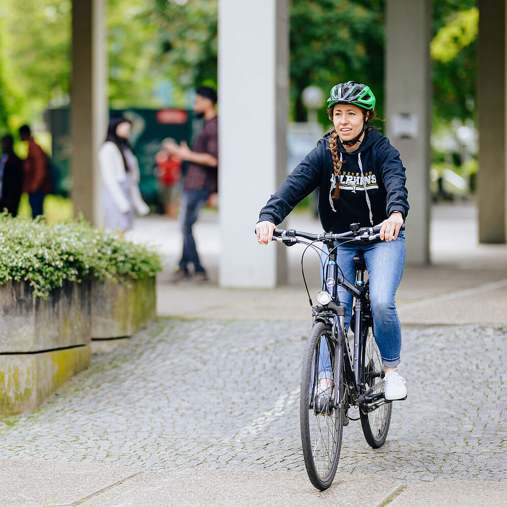 Eine Frau f?hrt Fahrrad ber den Campus der Universit?t Paderborn.